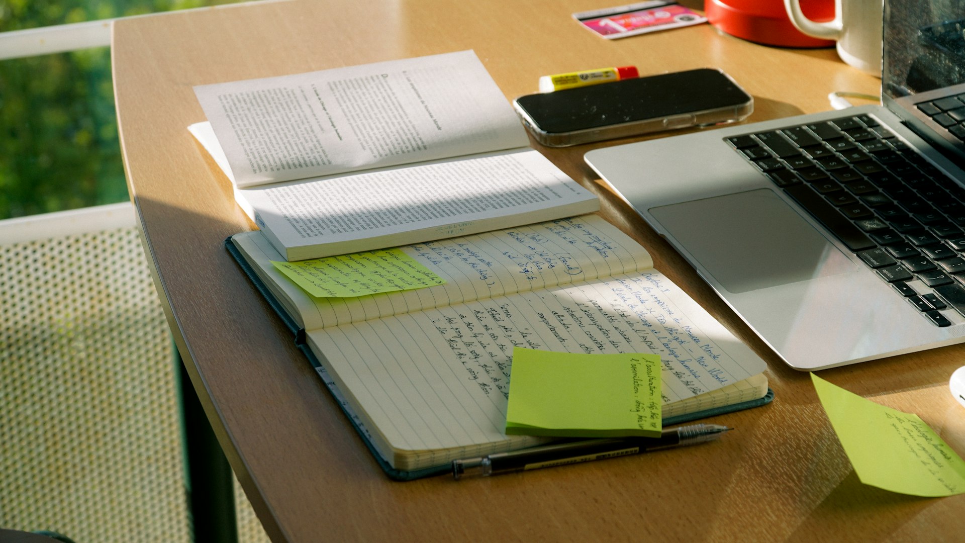 Notebook and laptop sit on a work desk.
